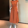Woman wearing an orange sleeveless cotton linen midi dress with a drawstring waist
