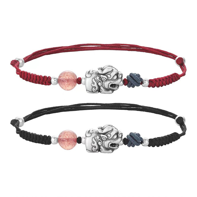 Two hands wearing red and black braided bracelets with silver Pixiu charms and pink beads