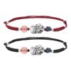 Two hands wearing red and black braided bracelets with silver Pixiu charms and pink beads
