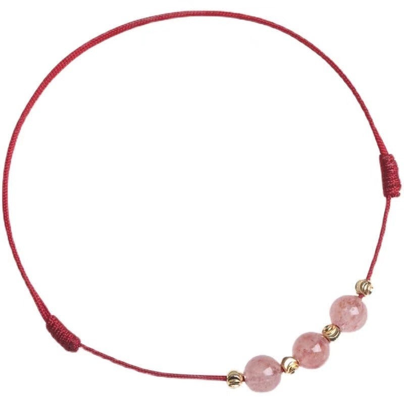Close up of a thin red cord bracelet with three pink crystal beads