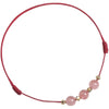 Close up of a thin red cord bracelet with three pink crystal beads