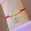 Gold snake charm and jade peace buckle on a red woven cord bracelet
