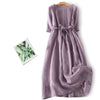 Purple pleated midi dress with tie waist hanging on wooden hanger
