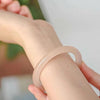 Close up of a hand wearing a pale pink jade bangle bracelet