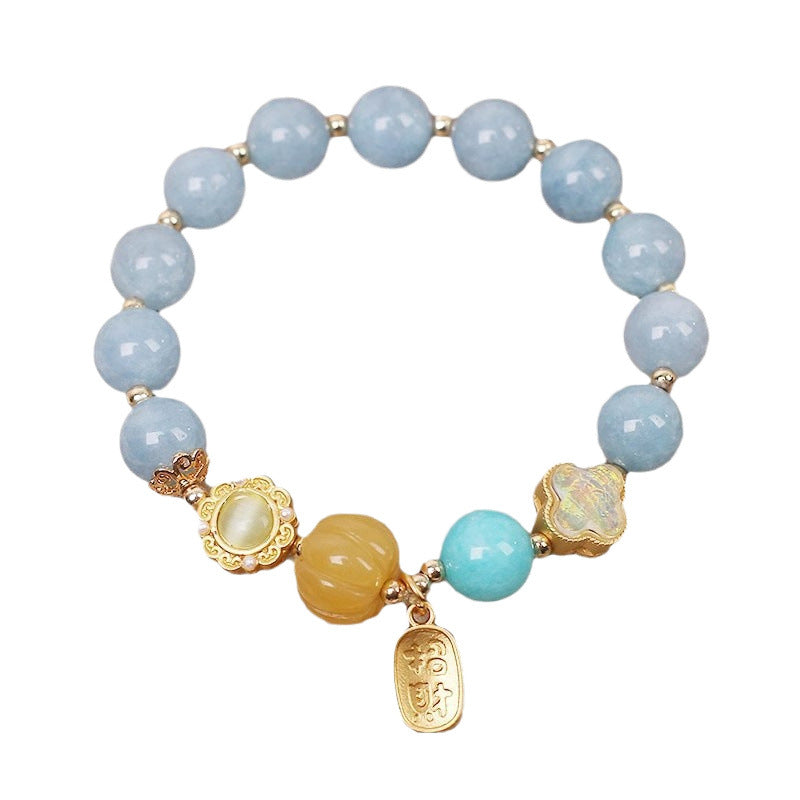 Light blue beaded bracelet with gold charms on white background