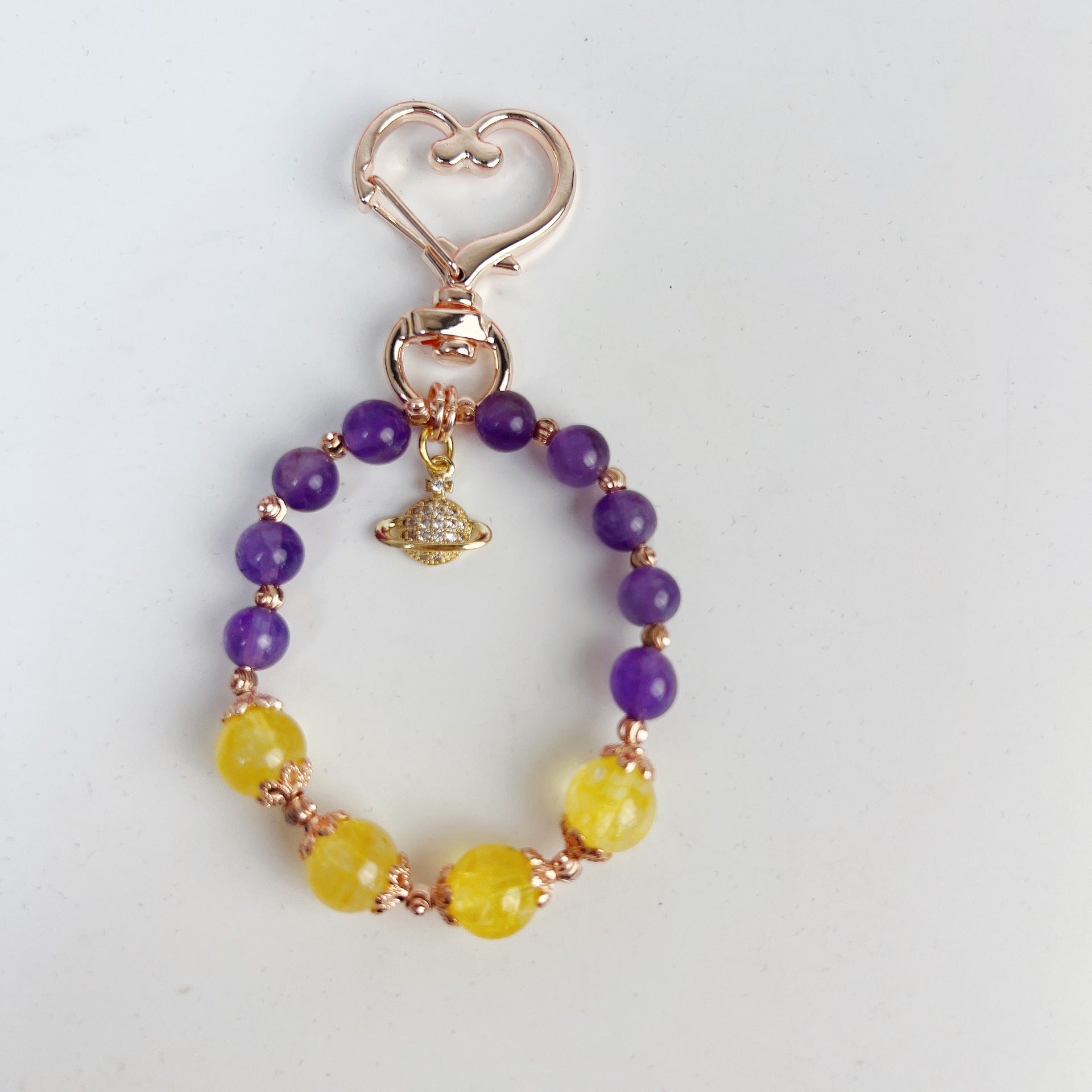 Close up of a beaded keychain with purple and yellow stones on a gold tone chain
