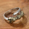 Close up of an adjustable ring with a silver band and copper vajra design on a wooden surface