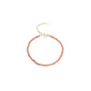 A close-up of a pink crystal beaded bracelet with a gold-tone clasp on a beige background.