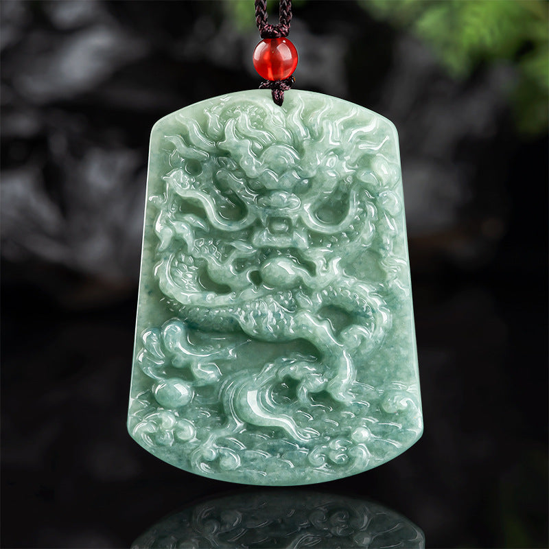 Carved green jade dragon pendant on a dark cord with a red bead