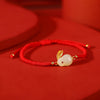 Hand-woven red string bracelet with a white jade rabbit charm and gold plated ears