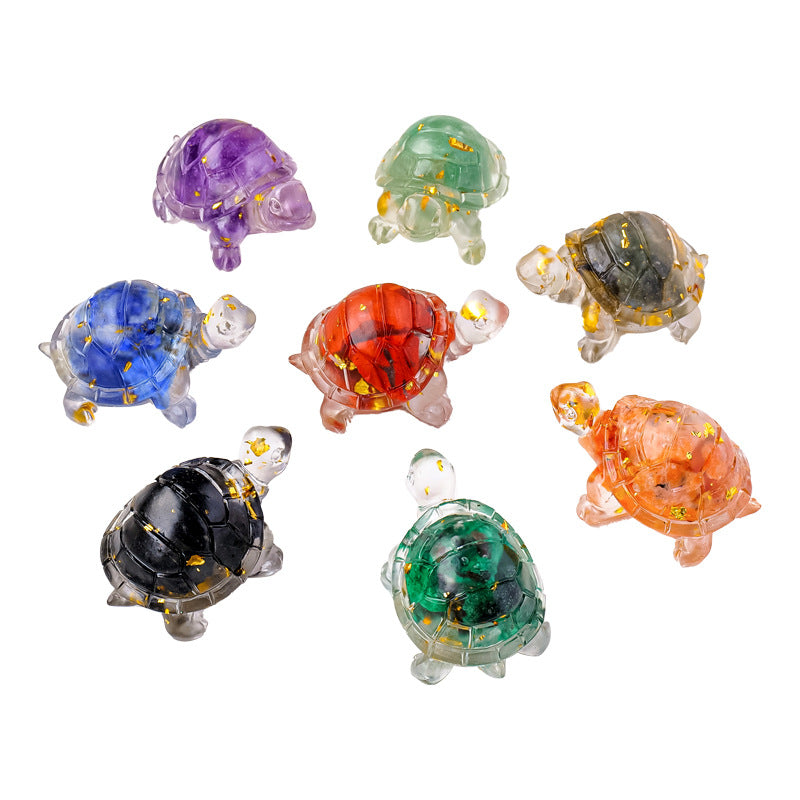 Assorted small crystal turtle figurines in various colors including purple, green, red, and black on a white surface.