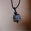 Close up of a silver sheen obsidian pendant carved into a lion head on a black cord