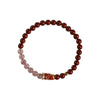 Close-up of a red cinnabar and pink strawberry quartz bracelet with a gold koi fish charm on a white background.