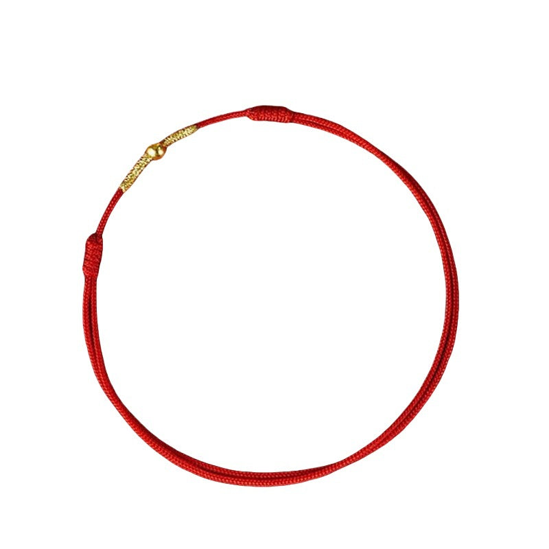 Close up of a red braided rope bracelet with a small gold bead center on a dark red background