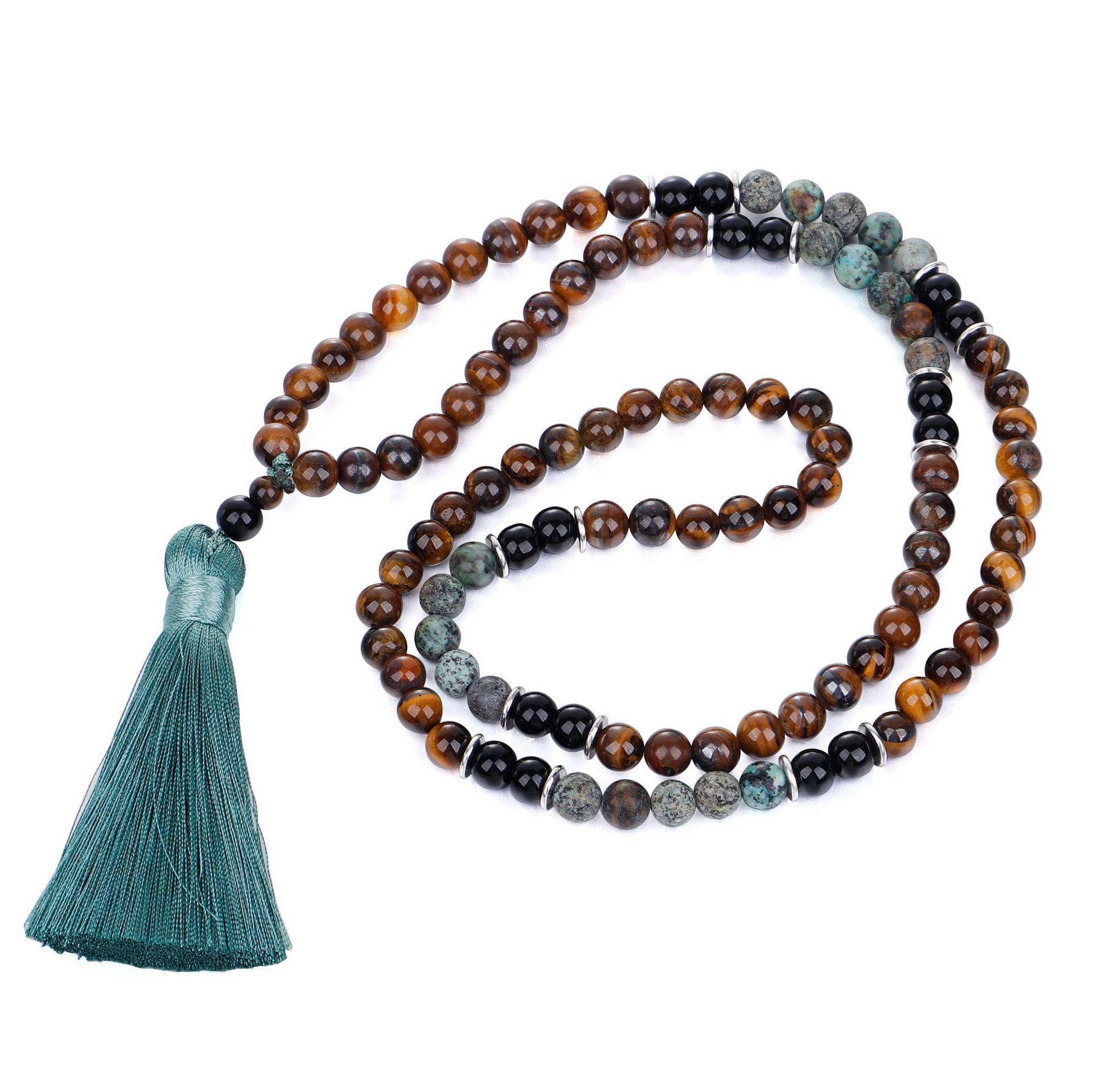 Long 108 bead mala necklace with tiger eye and turquoise stones and a green tassel lying on wood