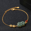 Gold tone chain bracelet with green jade Pixiu charm, copper coins and red agate bead