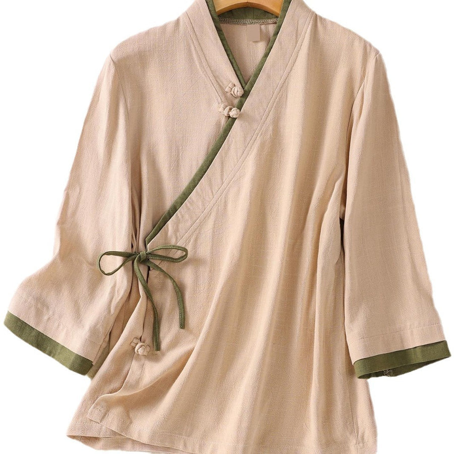 Beige women's top with green trim and frog button closure