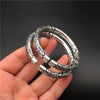 Hand holding a silver-tone adjustable bangle with a double dragon relief design
