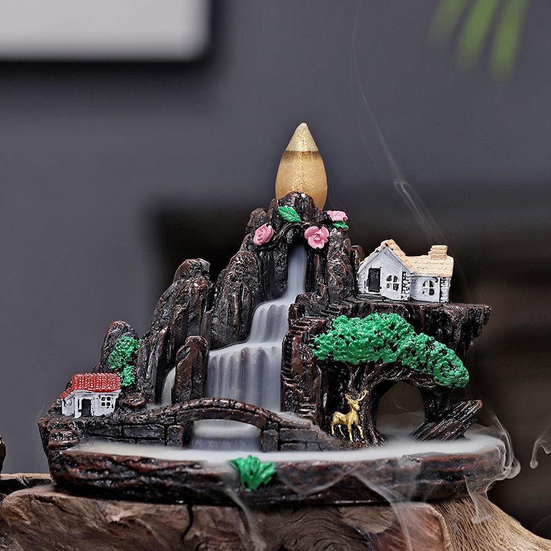 Backflow incense cone burning on a mountain landscape burner with smoke flowing down
