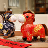 Red and blue plush horse dolls with gold-tone coin patterns sitting on a table