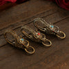 Three brass dragon head keychains with red and blue stones on a wooden surface