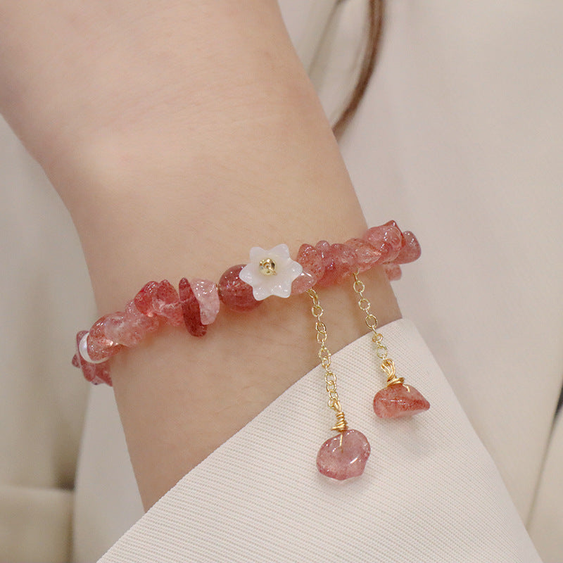 Close up of a pink strawberry quartz chip bracelet with a white flower charm on a wrist
