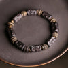 Close up of a dark wood bracelet with gold tone spacers on a plate