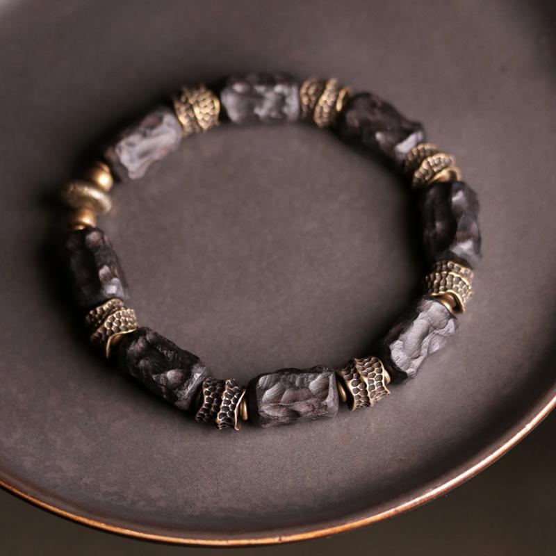 Close up of a dark wood bracelet with gold tone spacers on a plate