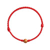 Close up view of a red braided cord bracelet with a small wooden bead