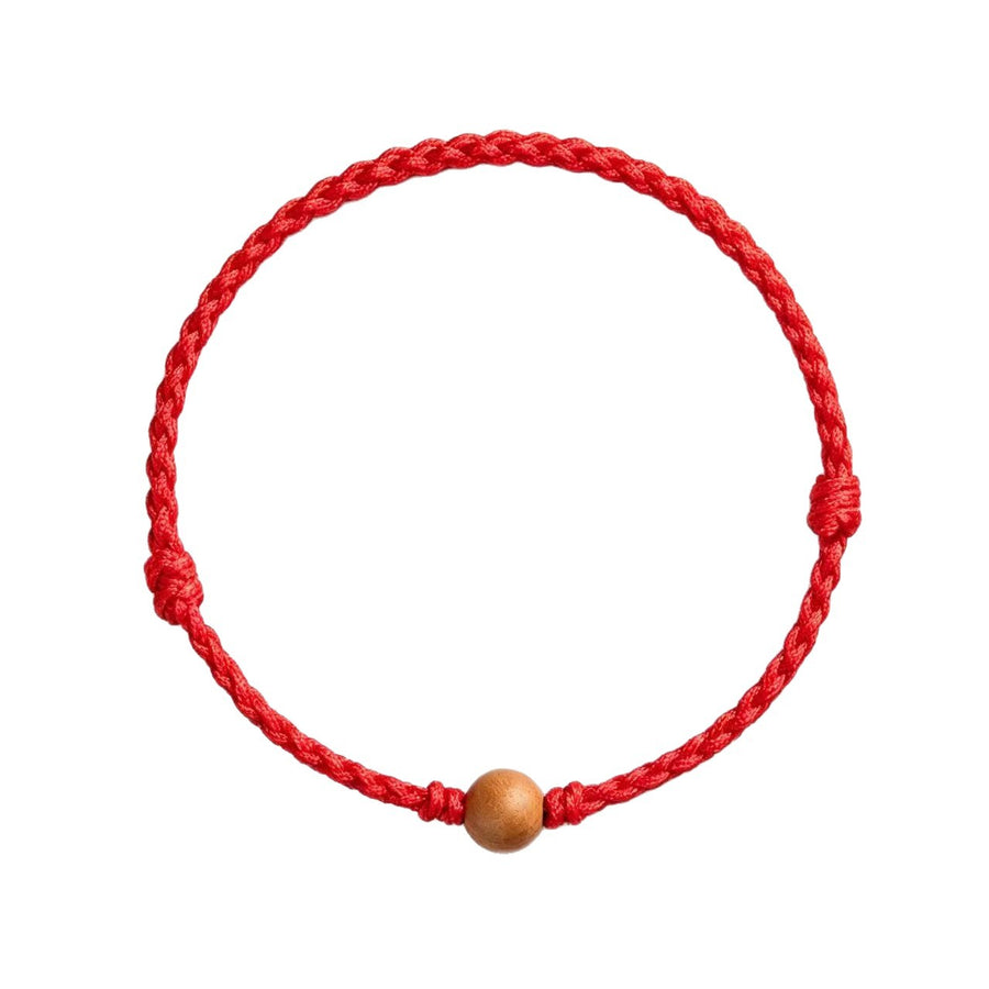 Close up view of a red braided cord bracelet with a small wooden bead