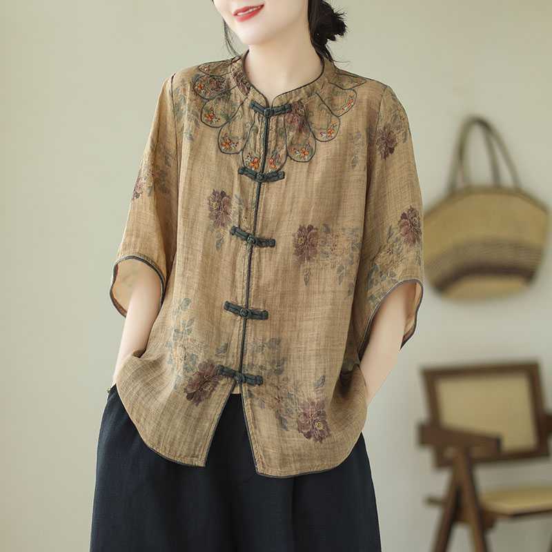 Woman wearing a loose beige shirt with purple flowers and dark frog buttons