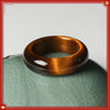 Polished brown tiger eye stone ring resting on a green ceramic surface