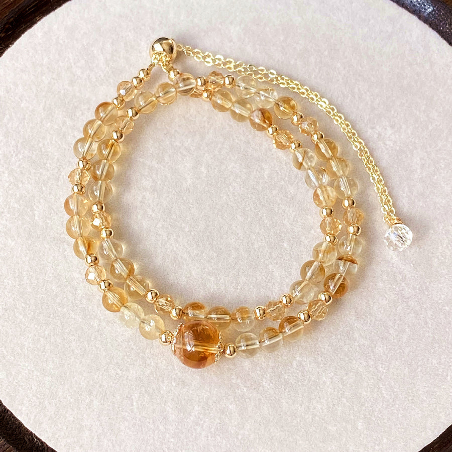 Double layer natural citrine beaded bracelet with gold tone chain on white surface