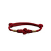 Close up view of a red braided cord bracelet with a central knot and gold accents