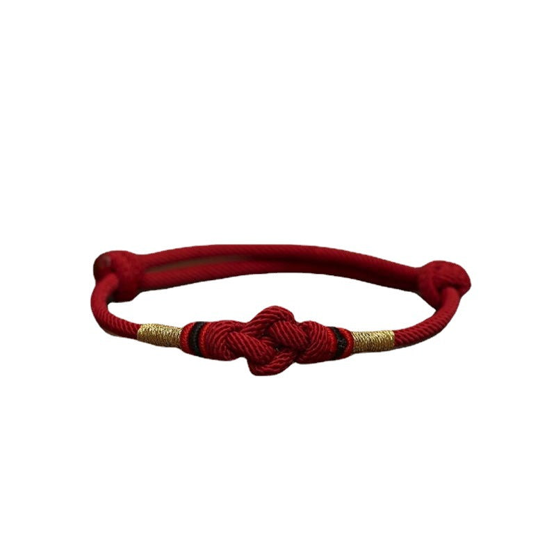 Close up view of a red braided cord bracelet with a central knot and gold accents