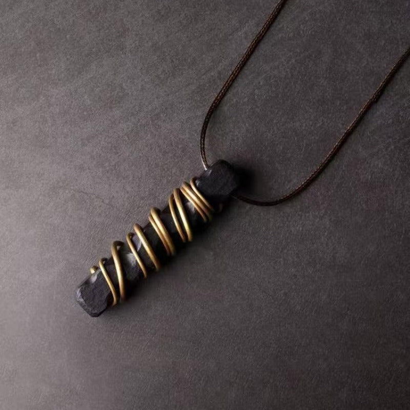 Black stone pendant with gold tone spiral wire wrapping on a cord