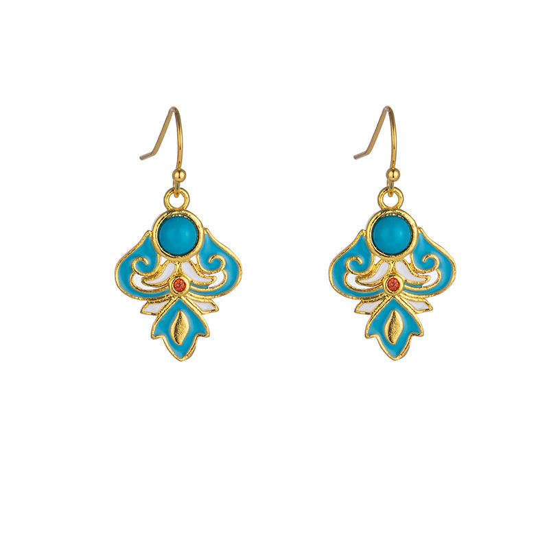 Pair of gold-tone drop earrings with blue enamel and faux turquoise stones resting on wood