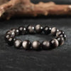 Close up view of a black beaded bracelet with silver highlights on a dark surface