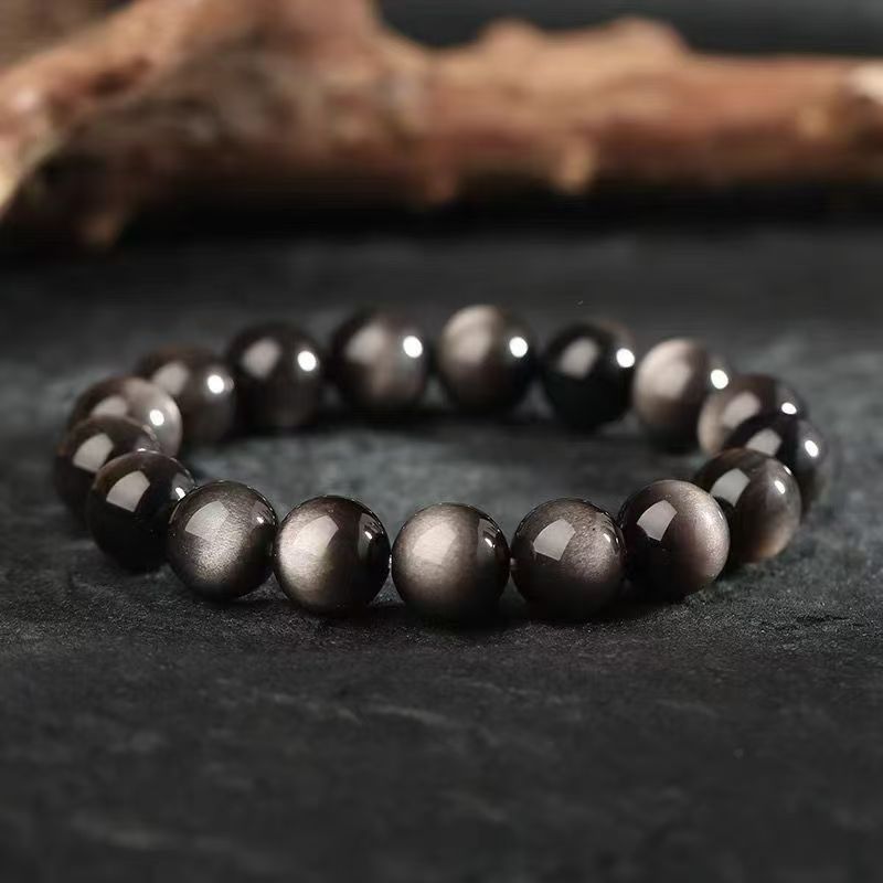 Close up view of a black beaded bracelet with silver highlights on a dark surface