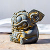 Close up of a rust colored resin Swallowing Beast statue on a wooden table
