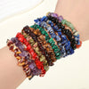 A wrist wearing multiple colorful natural irregular crystal stone bracelets