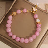 Pink quartzite beaded bracelet with white pearl accents and a gold-tone lotus pendant charm