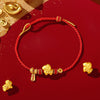Close up of a red woven bracelet with gold goat charms and silver beads on a red background