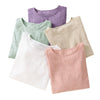 Five folded women's long sleeve shirts in white, pink, beige, green, and purple