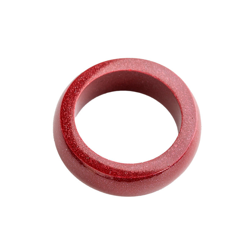 Close up of a red cinnabar ring with a silver zodiac symbol on a finger
