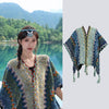 Model wearing a colorful striped knit poncho wrap by a lake