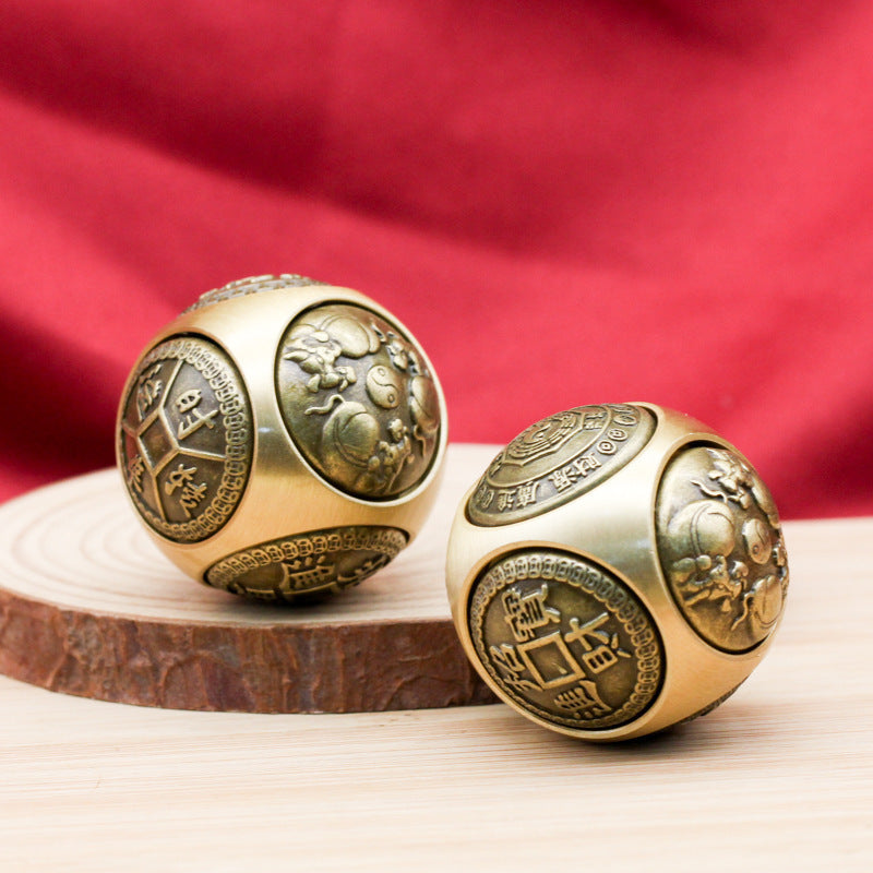 Two gold-tone brass spheres with rotating faces showing coin and yin yang symbols