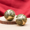 Two gold-tone brass spheres with rotating faces showing coin and yin yang symbols