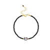 Close-up of a wrist wearing a black beaded bracelet with a gold-tone cat charm.