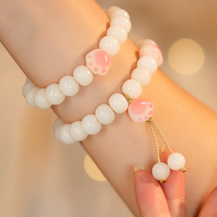 White bodhi seed bracelet with a pink cat paw bead on a wrist